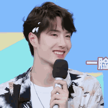 a young man holds a microphone in front of a blue background