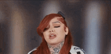 a woman with red hair and tattoos on her face is making a face .