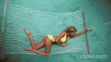 a woman in a bikini is laying in a hammock in the water
