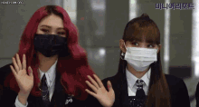 two girls wearing face masks are waving their hands in front of a sign that says ' honeycam.org '