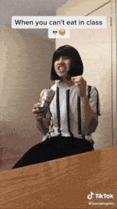 a woman is sitting at a table with a can of soda in her hand and a tiktok sticker above her head