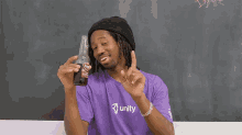 a man in a purple shirt that says unity holds a bottle