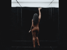a woman in a bodysuit is dancing in a room with mirrors