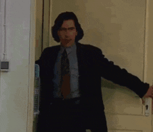 a man in a suit and tie is standing in front of a door .