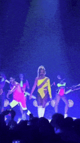 a woman in a yellow jumpsuit is dancing on stage