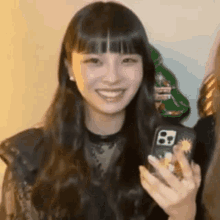 a woman is smiling while holding a cell phone case in her hand .