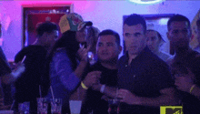 a group of people are standing in a dark room with purple lights .