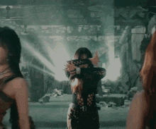 a woman in a black outfit is dancing in a dark room with other women