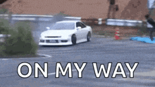 a white car is drifting down a road with the words `` on my way '' written on the bottom .