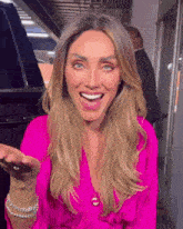 a woman wearing a pink shirt and bracelets is smiling