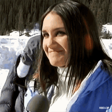 a woman in a blue jacket is standing in the snow