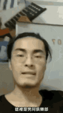 a man wearing glasses and a black shirt is making a funny face in a foreign language