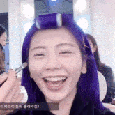 a woman with purple hair is smiling while getting her hair curled