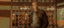a man in a brown leather jacket is standing in a room with his hands in his pockets and looking up .