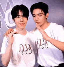 two young men wearing white shirts with the letter w on them are posing for a photo