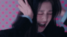 a woman is covering her ears with her hand and crying .