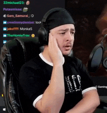 a man wearing headphones and a headband is sitting in a chair in front of a microphone .