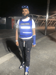a man is wearing a blue vest that says pull here on it