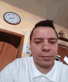 a man taking a selfie in front of a clock that says cucina on it