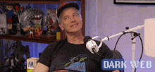 a man is sitting in front of a microphone in a dark web room .