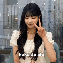 a woman giving a peace sign with the words koko de ale written below her