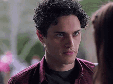 a young man with curly hair is looking at a woman in a plaid shirt .