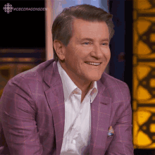 a man in a purple suit and white shirt is smiling with the hashtag #cbcdragonsden above him