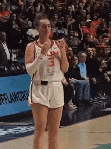 a female basketball player wearing a number 3 jersey stands on the court
