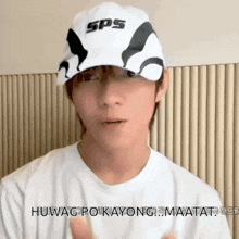 a man wearing a sps hat and a white shirt giving a thumbs up