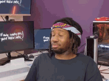 a man wearing a headband is sitting in front of a computer monitor that says " you 've been max "