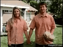 a man and woman are holding hands in front of a house