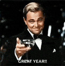 a man in a tuxedo is holding a glass of wine and making a toast .