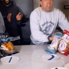 a man wearing a shirt that says seoulman is holding a bag of chips