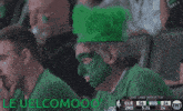 a man with green paint on his face sits in the stands watching a basketball game