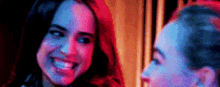 two women are standing next to each other in a dark room and smiling at each other .