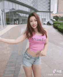 a woman wearing a pink top that says envelo