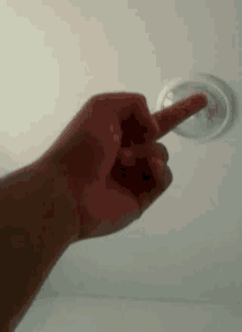 a close up of a person 's hand pointing at a light on the ceiling .
