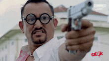 a man with glasses is pointing a gun at the camera with an astro channel advertisement in the corner