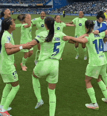 a group of female soccer players are huddled together on the field and one of them has the number 5 on her back