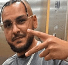 a man with a beard and glasses is giving a peace sign .