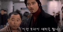 a man with a beard is standing next to another man in a crowded room .