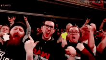 a group of people are standing in a crowd and one of them has a shirt that says raw on it