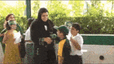 a woman in a black hijab is holding a microphone and talking to a group of children