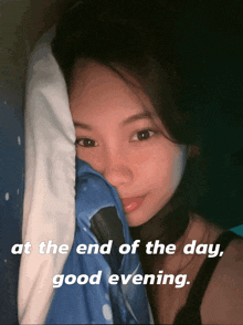 a woman covering her face with a pillow with the words at the end of the day good evening below her