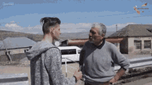 a man in a grey sweatshirt is talking to a man in a gray sweater