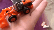 a person is holding a small toy tractor in their hand .