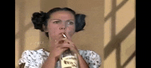 a woman is smoking a cigarette while holding a bottle of liquor .