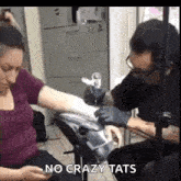a woman is getting a tattoo on her arm by a man .