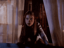 a woman looking out of a window with a dark background