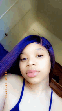a woman with purple hair is wearing a blue tank top and taking a selfie